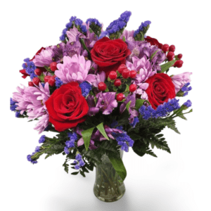 Red roses and purple flowers in vase.